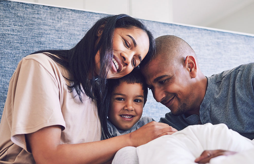 A mom, son and father smile and hug each other.