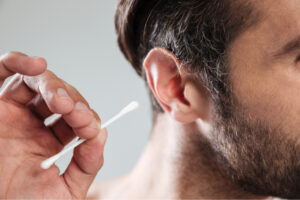 A man holds a cotton swab near his ear